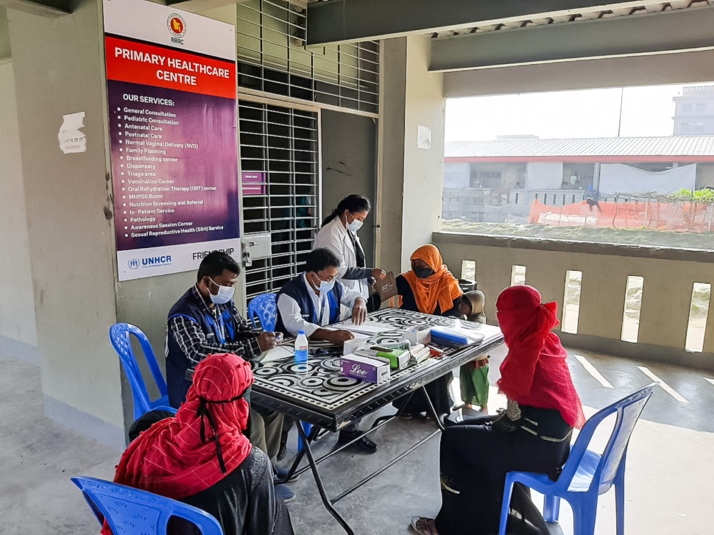 Rohingya patients sitting around a table at a primary health clinic in Bhashan Char