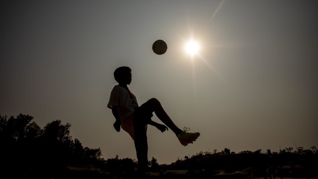 A child plays football, supplied with kit from the PSG-Friendship Mobile Sports Library